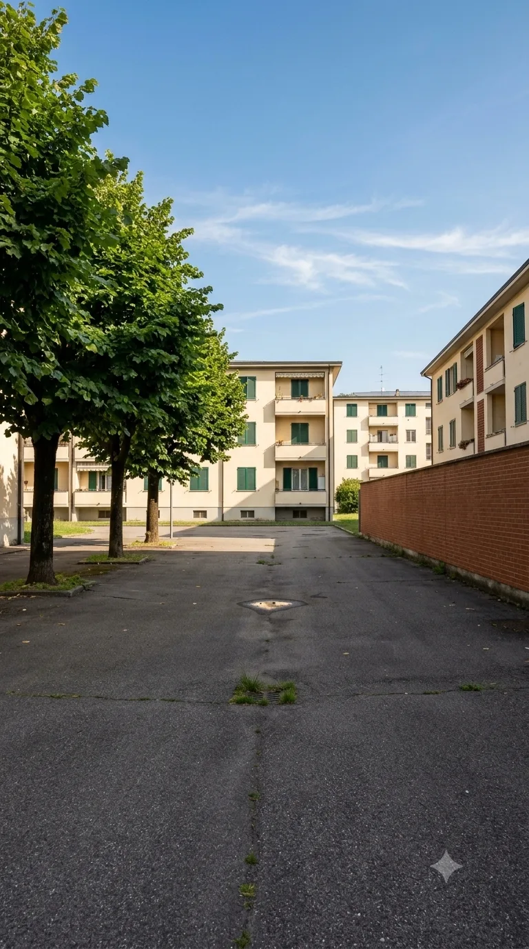Immagine statica verticale 9:16 per YouTube Shorts, usata per un timelapse di costruzione. Cortile asfaltato di un isolato residenziale di pianura, inquadrato da una camera fissa a circa 2 metri di altezza, obliqua a 35 gradi, distante circa 16 metri dal centro dello slargo. L’orizzonte taglia il terzo superiore. In primo piano a sinistra un filare di tre tigli con tronco scuro e chioma piena; a destra un muro di recinzione in laterizio rosso alto 2 metri che corre in profondità. Sullo sfondo due palazzine residenziali a tre piani intonacate color crema con balconi e persiane verdi. Al centro dell’inquadratura resta uno slargo asfaltato grigio scuro, leggermente consunto, con qualche ciuffo d’erba nei giunti e una pozzanghera secca. Luce pomeridiana chiara da sinistra, ombre di contatto nette e corte, cielo azzurro con nubi sottili, color grading fotografico naturale leggermente caldo. Nessun movimento di camera.